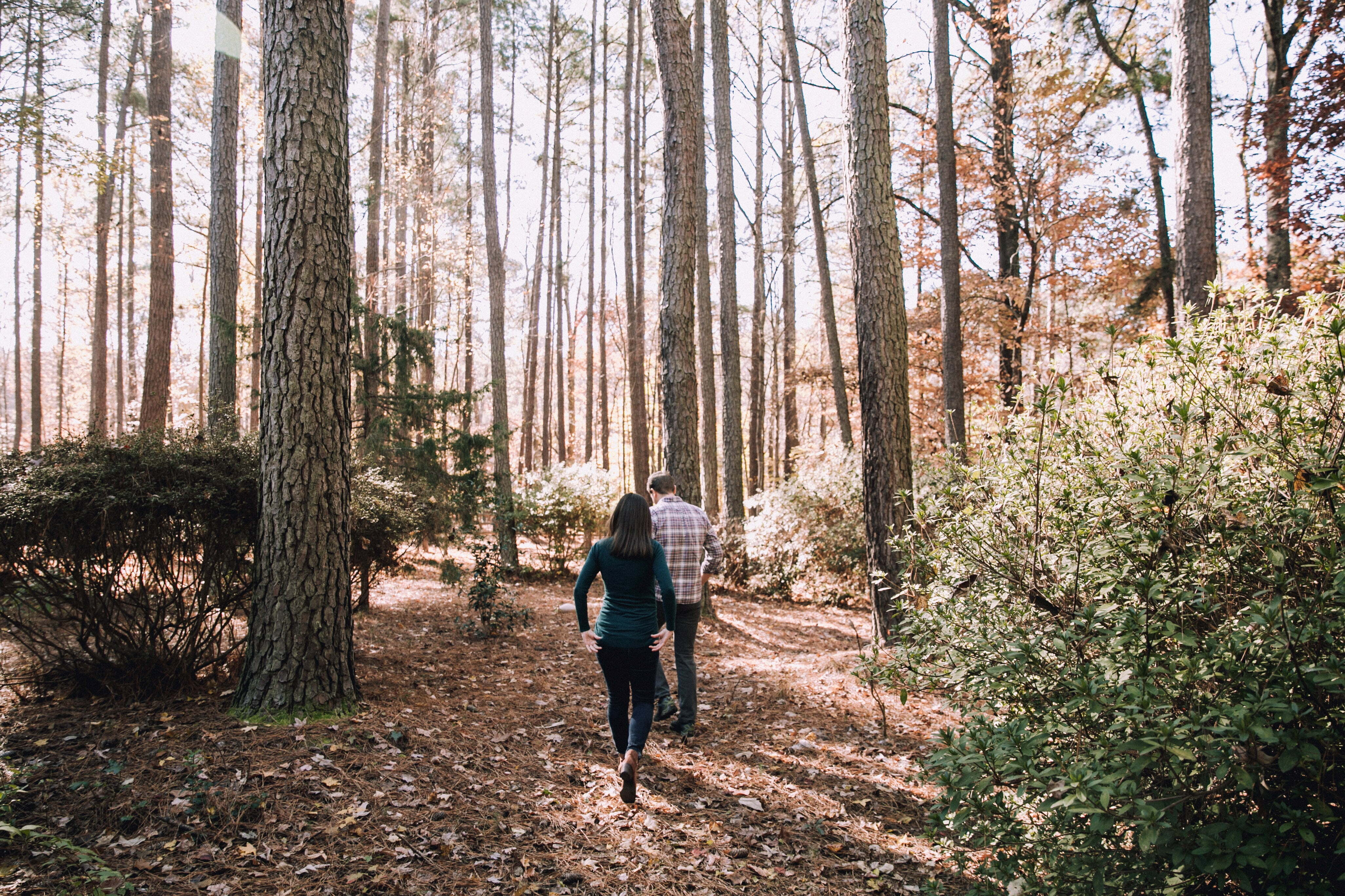 a man and woman walking on a trail in the woods