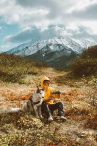 a person sitting on a rock with a dog on the lap