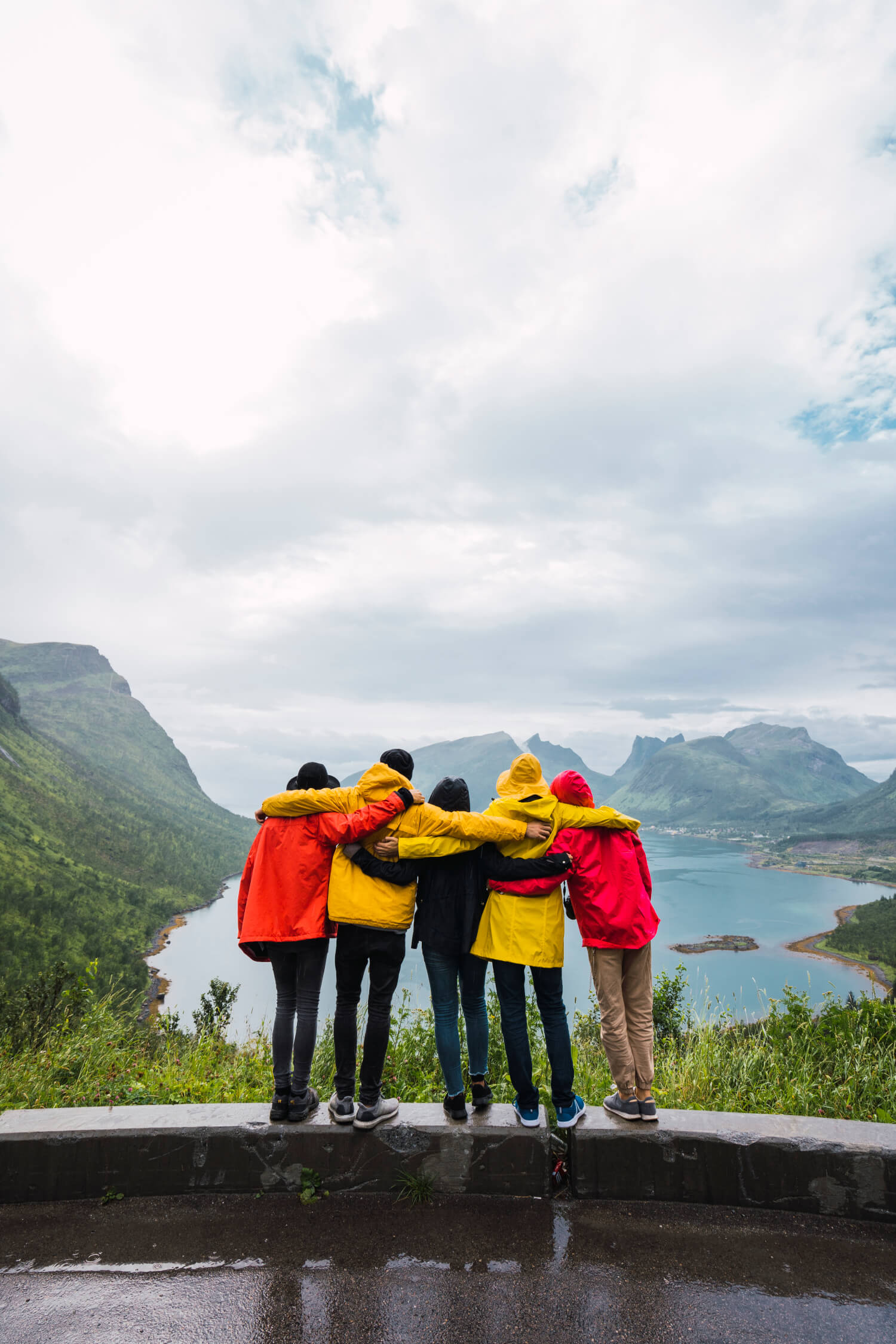 a group of people standing on a rock ledge overlooking a lake